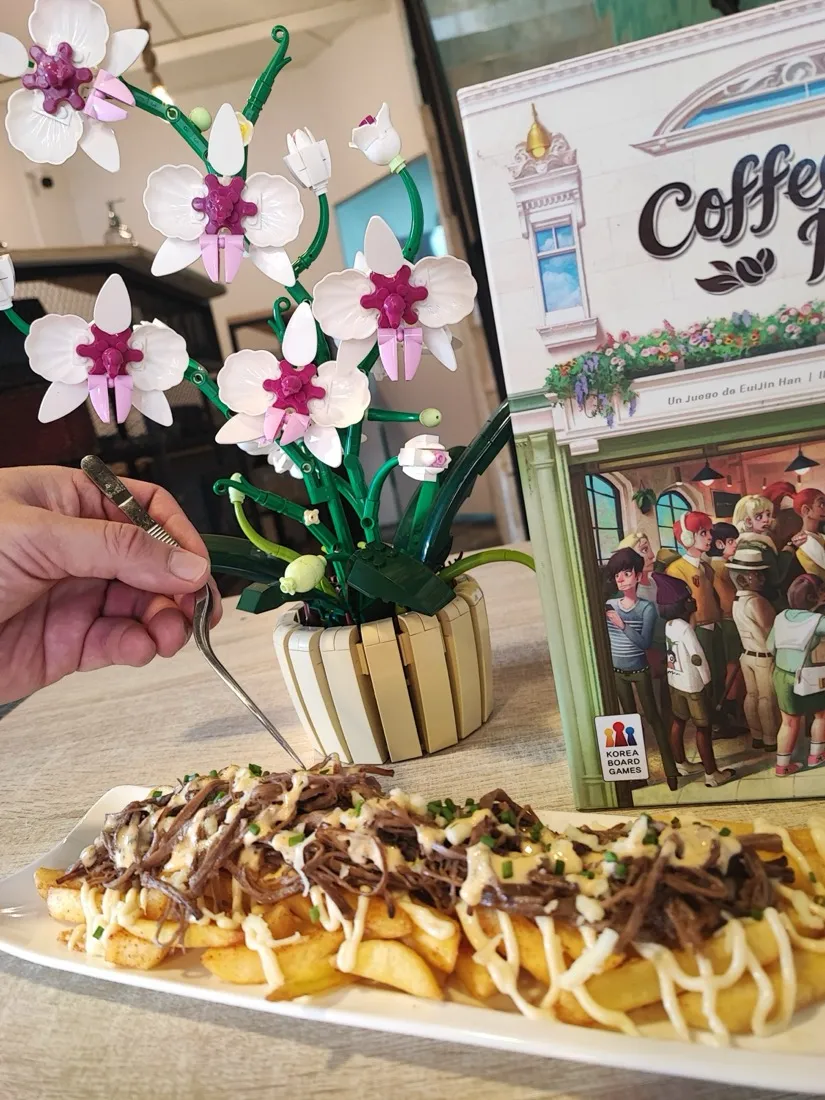 Papas a la francesa con carne desmechada y salsas, servidas junto a un juego de mesa
